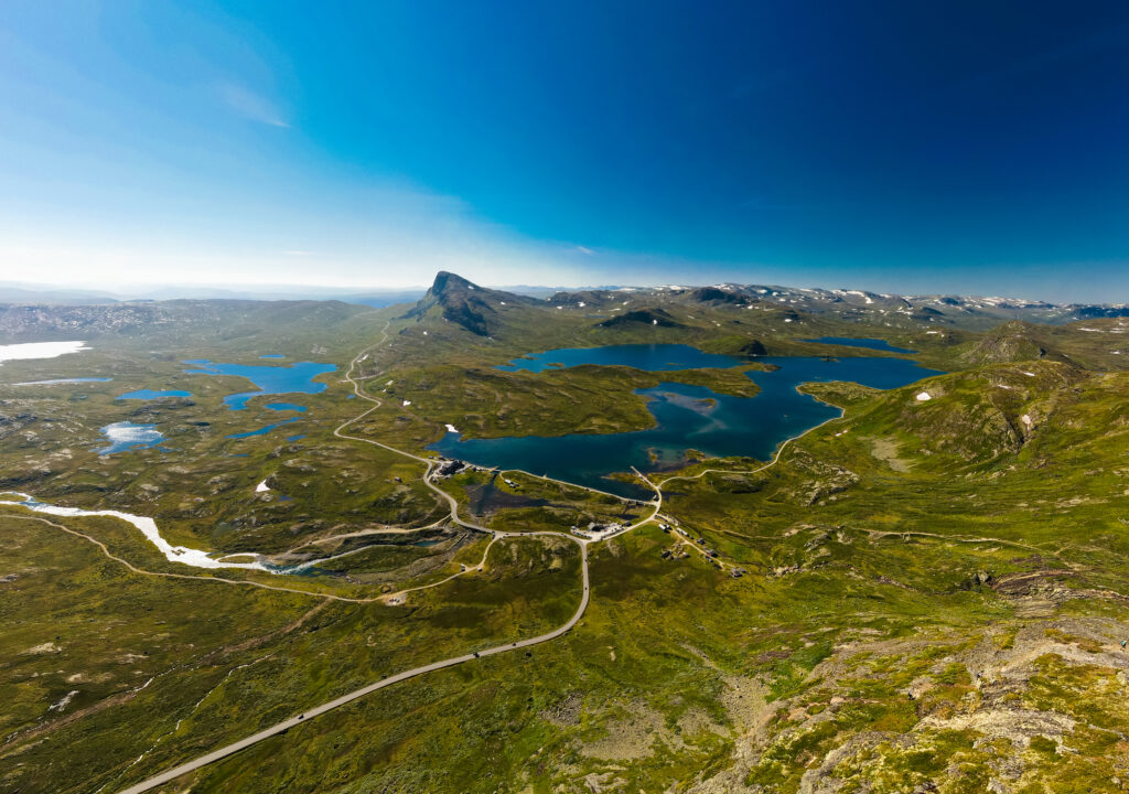 Jotunheimen i fugleperspektiv. Grønne fjell under blå himmel.