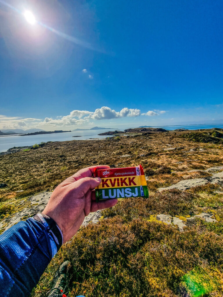 Magnar holder en Kvikklunsj med vakkert fjellandskap i bakgrunnen.