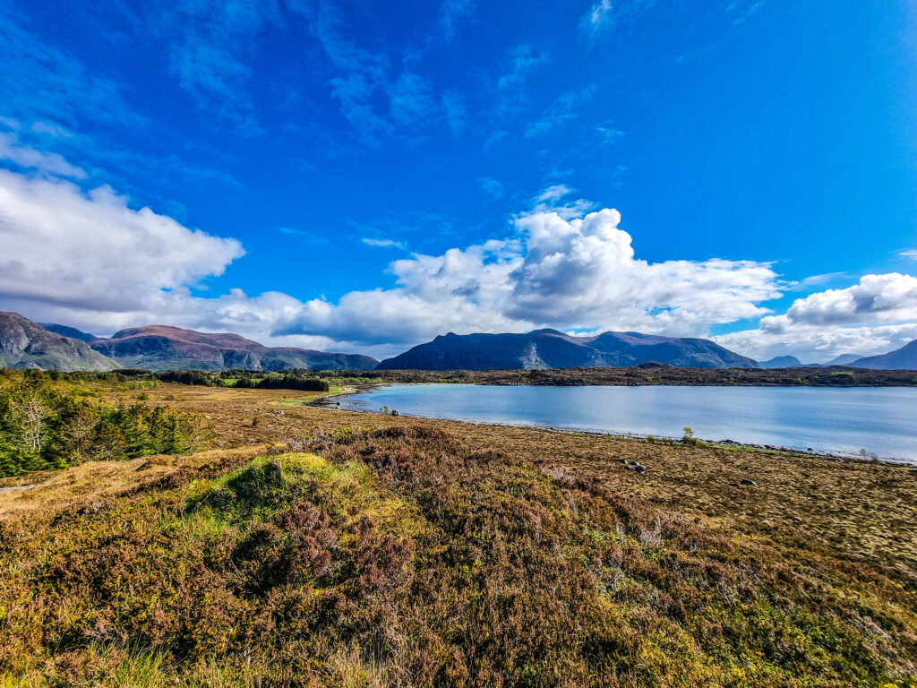Blå himmel reflekteres, lite vann og fjellandskap.