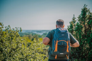 Mann med fjelltidsekken, i skog med utsikt.