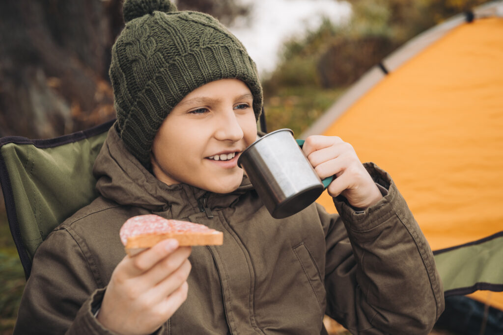 Gutt drikker spiser og drikker på campingtur med telt.