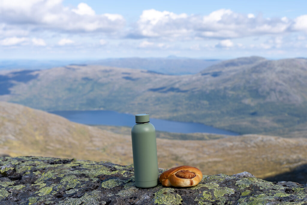 Turflaske og kanelsnurre med fjellandskap og Østre Sonvannet i bakgrunn.