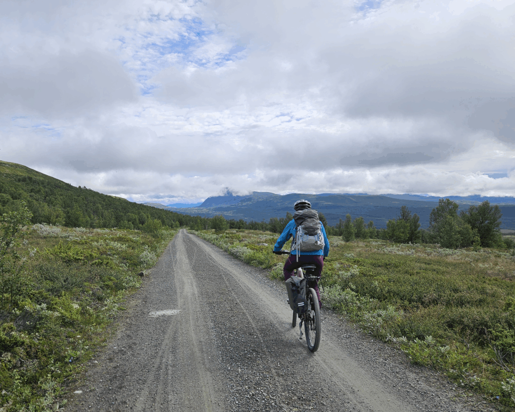 Tour de dovre. Sykkeltur over Dovre. Syklist på grusvei omgitt av vakkert fjellandskap.