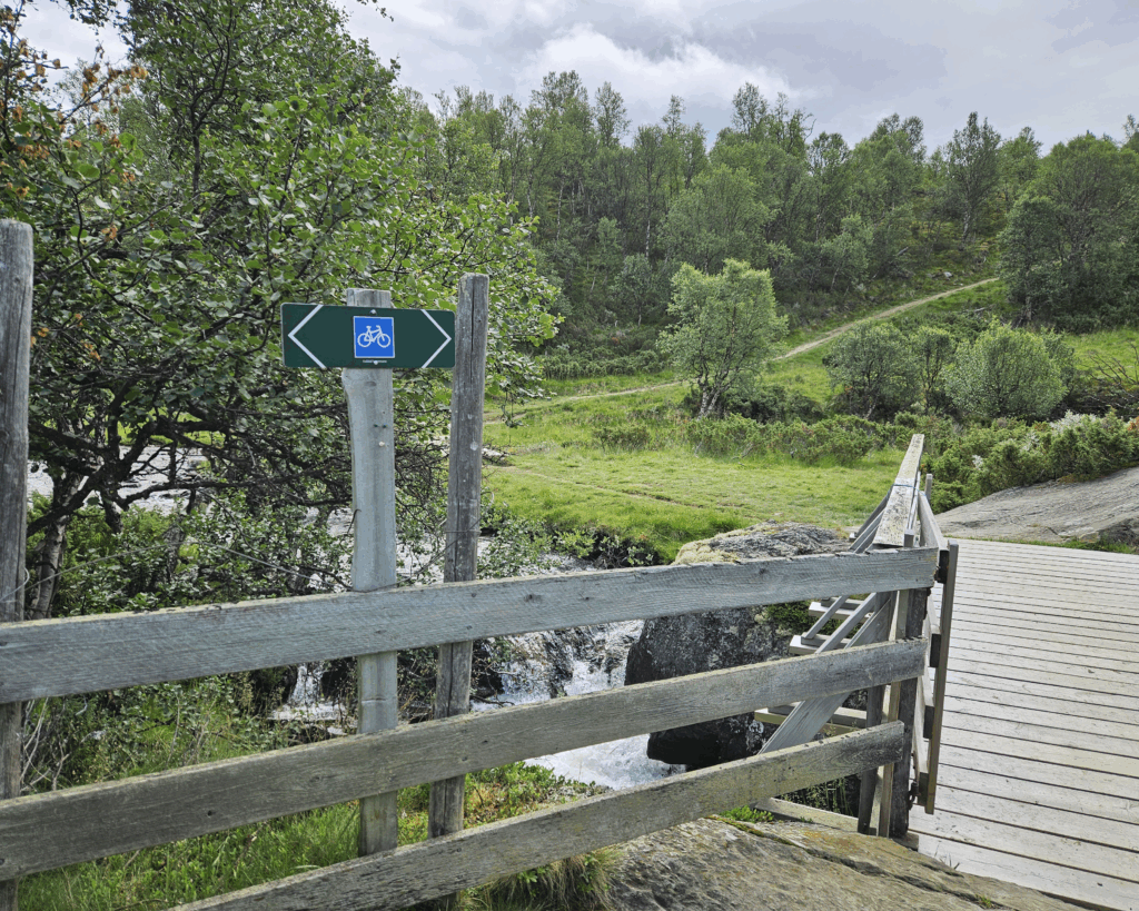 Bru over en liten elv omgitt av grønn natur.