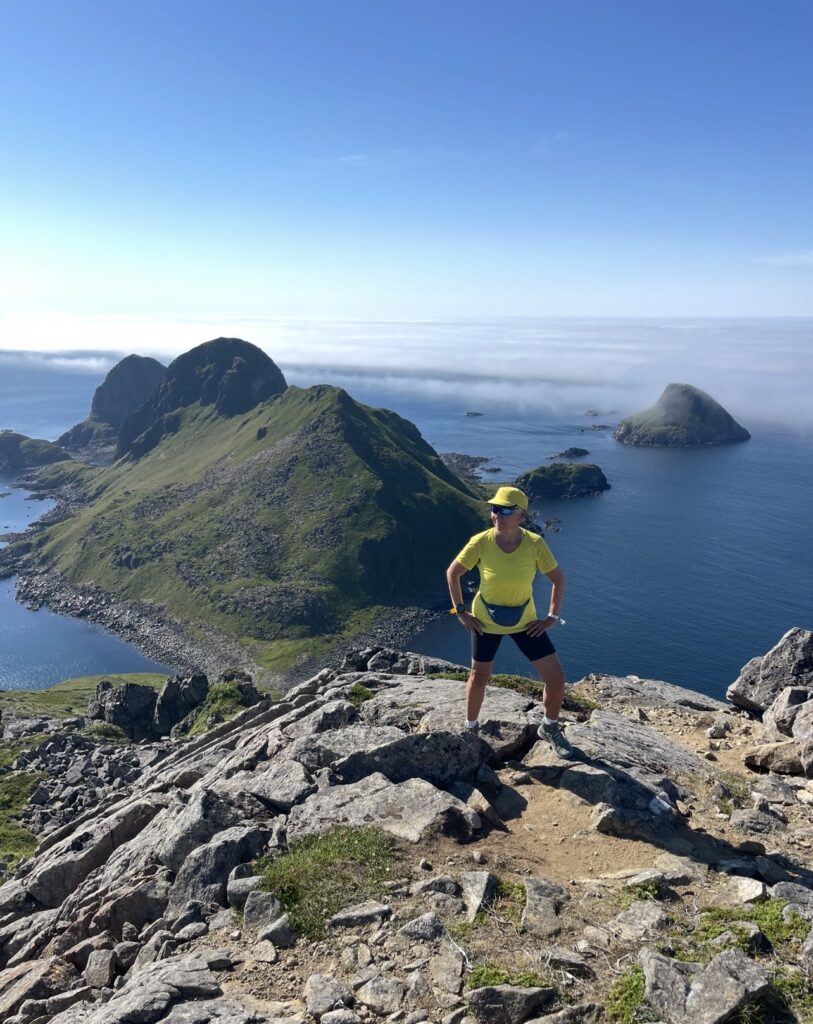 Marianne i fjellandskap og spektakulær utsikt over hav.