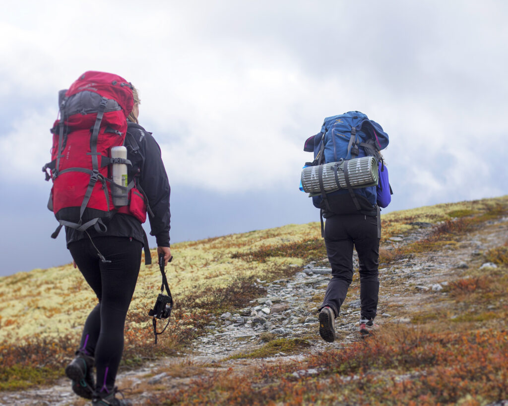Turgåere med sekk og utstyr i en høstkledd fjellheim