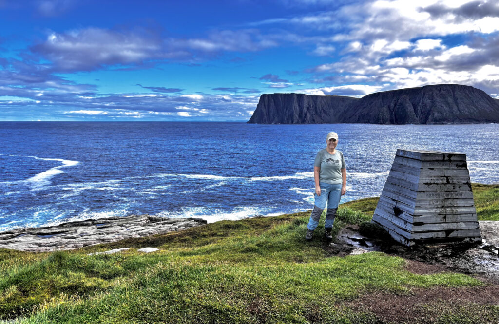 June Helen poserer ved varden ved Knivskjelodden i Finnmark. Norges nordligste punkt.