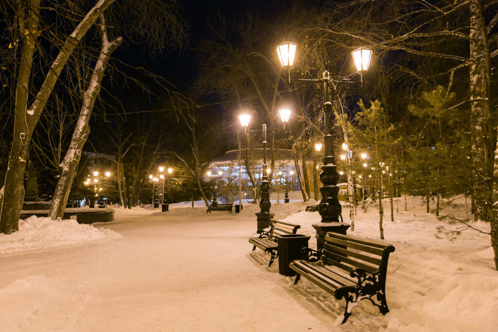 Night winter landscape in amazing city. Street lamp and bench covered snow. Silence and tranquility calm